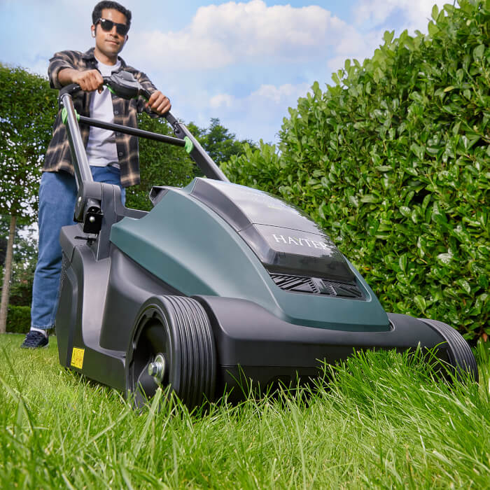 Man using the Hayter Hawk 43 AutoDrive lawnmower on long grass