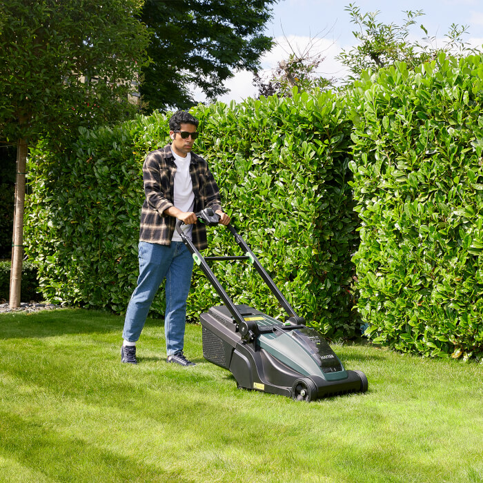 Man mowing the lawn with the Hayter Hawk 43 AutoDrive in a garden setting