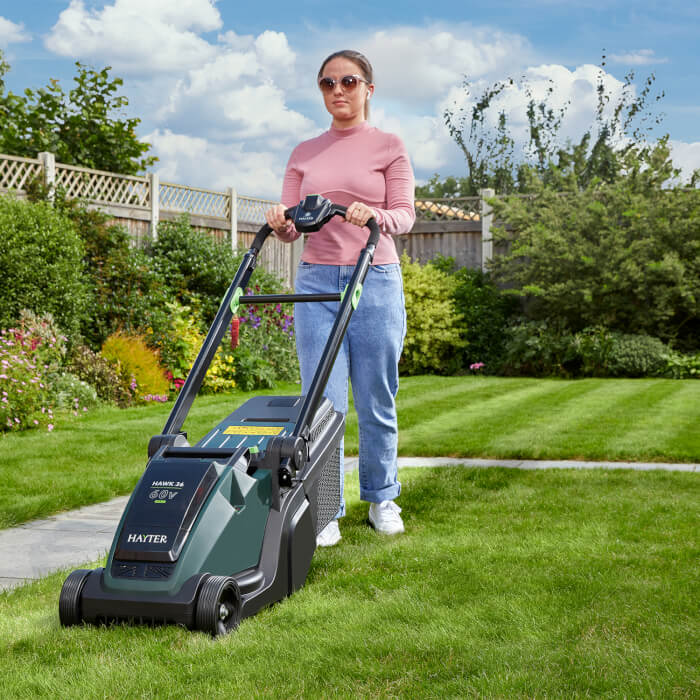 Woman using the Hayter Hawk 36 cordless lawnmower on her garden lawn